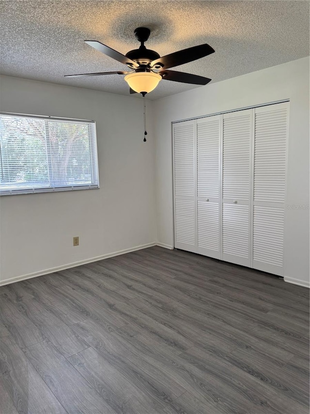 unfurnished bedroom featuring ceiling fan, dark wood-type flooring, a textured ceiling, and a closet