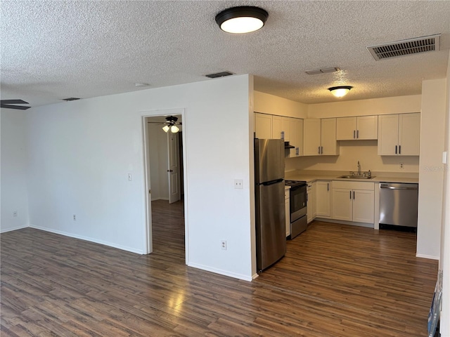 kitchen featuring dark wood-type flooring, sink, white cabinetry, ceiling fan, and stainless steel appliances