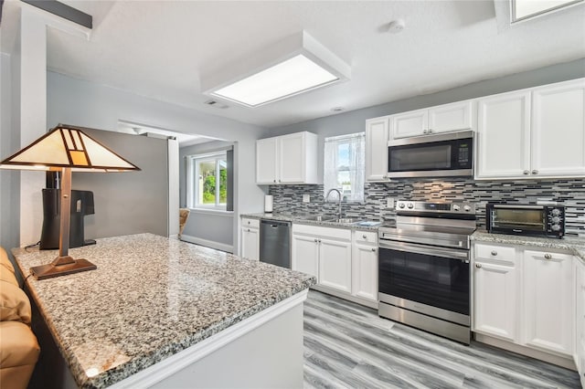 kitchen featuring appliances with stainless steel finishes, tasteful backsplash, white cabinetry, sink, and light stone counters