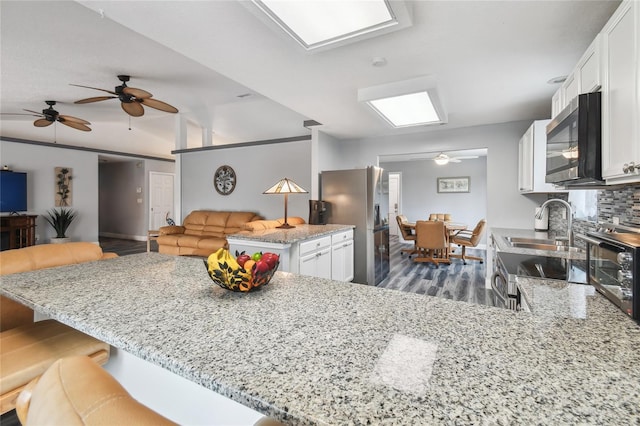 kitchen featuring white cabinetry, decorative backsplash, kitchen peninsula, and appliances with stainless steel finishes