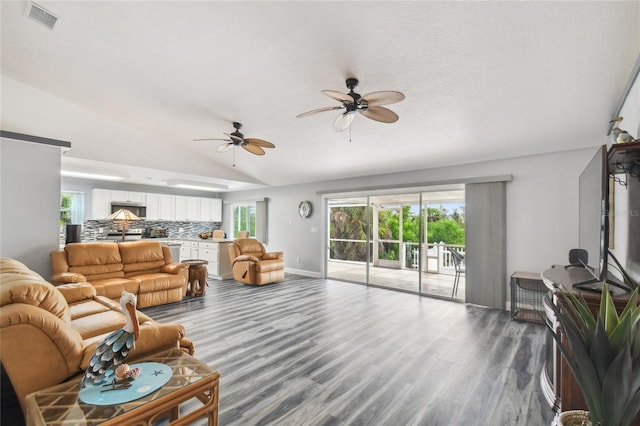 living room featuring hardwood / wood-style flooring, lofted ceiling, a healthy amount of sunlight, and a textured ceiling