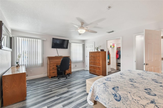 bedroom featuring ceiling fan, dark hardwood / wood-style flooring, multiple windows, and a textured ceiling