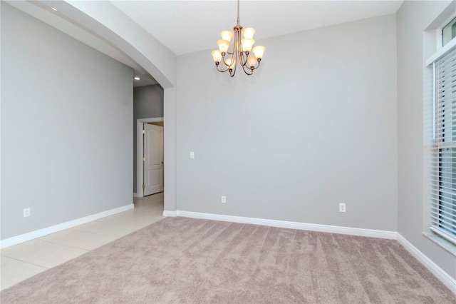 carpeted spare room with an inviting chandelier