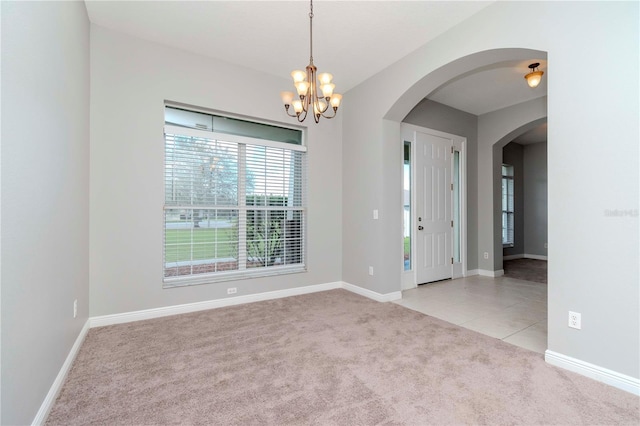 carpeted empty room featuring an inviting chandelier