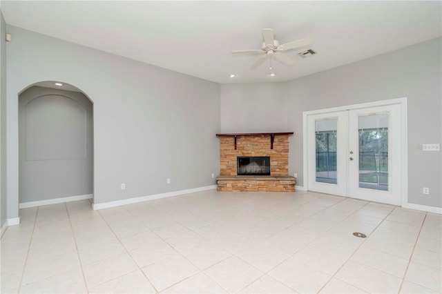 unfurnished living room featuring light tile patterned flooring, a fireplace, ceiling fan, and french doors