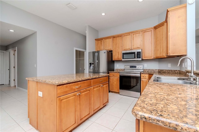 kitchen with sink, light tile patterned floors, stainless steel appliances, a center island, and light stone countertops