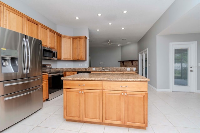 kitchen featuring stone countertops, sink, a center island, light tile patterned floors, and stainless steel appliances