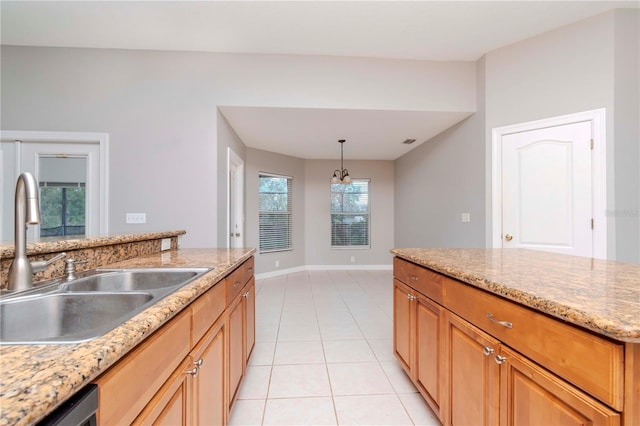 kitchen with sink, hanging light fixtures, light stone counters, light tile patterned flooring, and stainless steel dishwasher