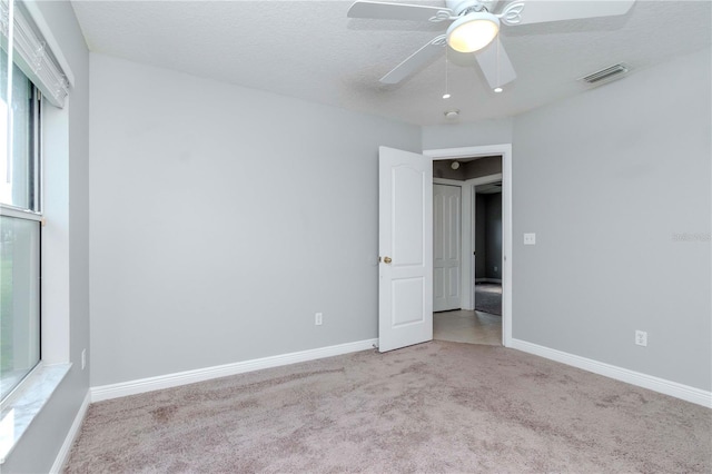 carpeted empty room with ceiling fan and a textured ceiling