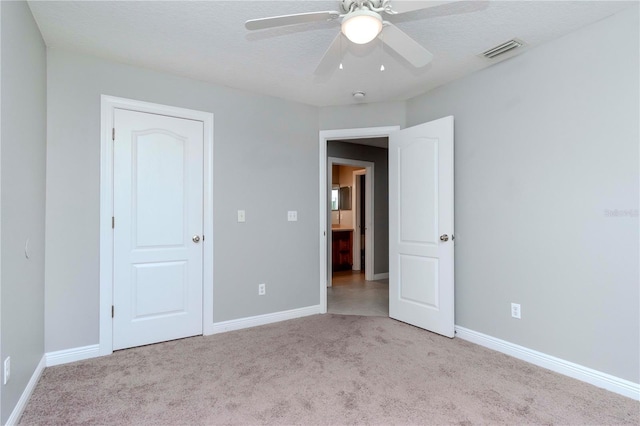 unfurnished bedroom with light carpet, ceiling fan, and a textured ceiling