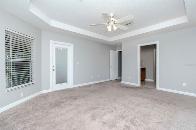 carpeted spare room with ceiling fan, a raised ceiling, and a textured ceiling