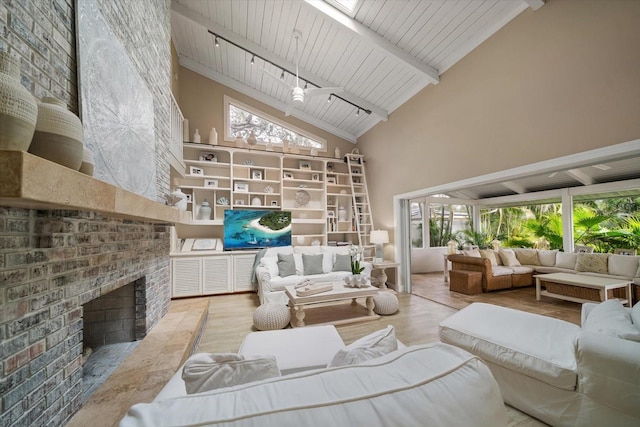 interior space with light hardwood / wood-style flooring, beam ceiling, a skylight, high vaulted ceiling, and a brick fireplace