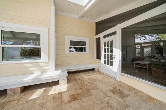 unfurnished sunroom with beam ceiling and a skylight