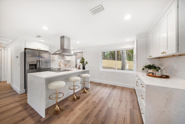 kitchen featuring white cabinetry, island range hood, a kitchen bar, and decorative backsplash