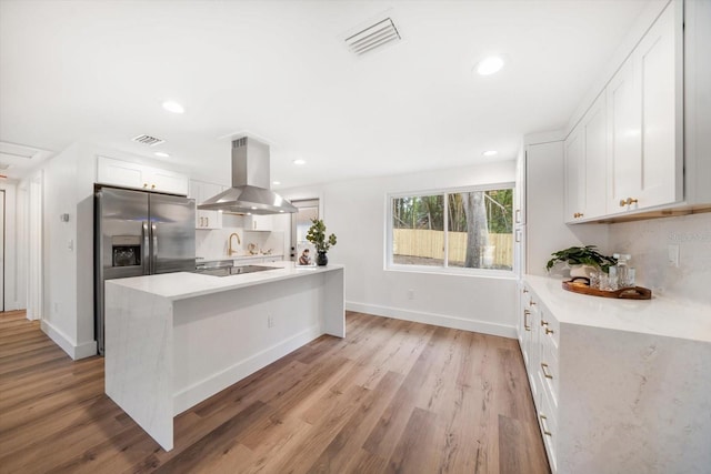 kitchen featuring white cabinetry, island exhaust hood, backsplash, and light hardwood / wood-style flooring