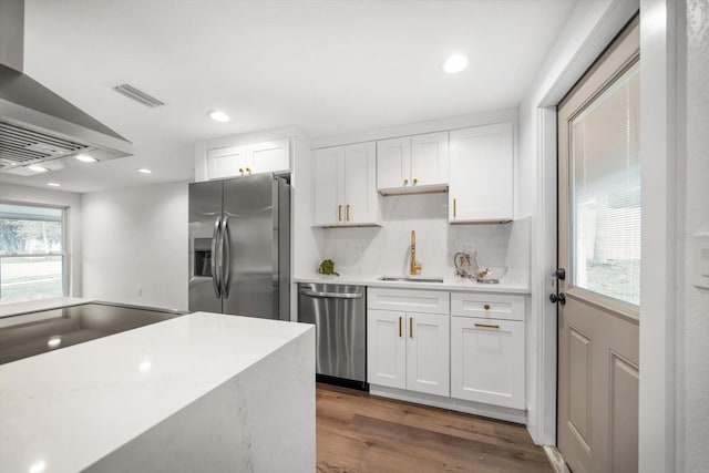 kitchen with island exhaust hood, stainless steel appliances, sink, and white cabinets