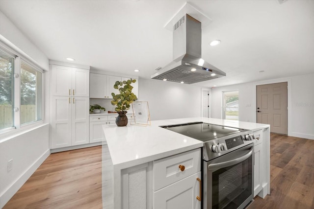 kitchen featuring island exhaust hood, stainless steel range with electric cooktop, and white cabinets