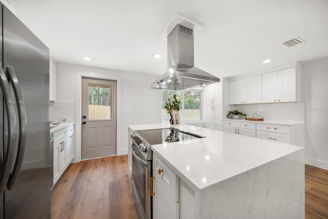 kitchen featuring appliances with stainless steel finishes, white cabinetry, dark hardwood / wood-style floors, a healthy amount of sunlight, and island exhaust hood