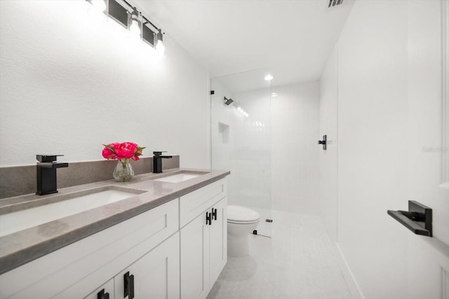 bathroom with tiled shower, vanity, toilet, and tile patterned floors