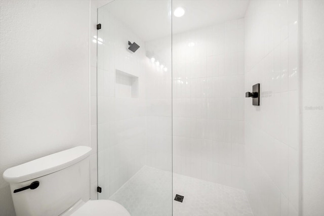 bathroom with a tile shower and toilet