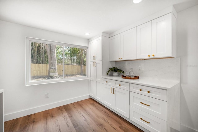 kitchen with white cabinetry, decorative backsplash, and light hardwood / wood-style floors