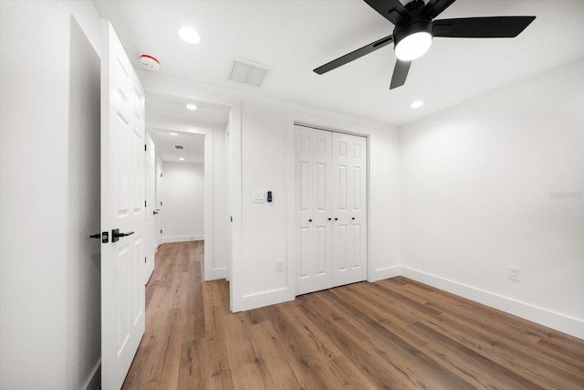 unfurnished bedroom featuring wood-type flooring, a closet, and ceiling fan