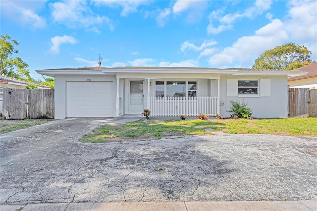ranch-style house featuring aphalt driveway, fence, covered porch, stucco siding, and an attached garage