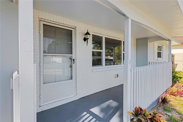 property entrance featuring a porch and brick siding