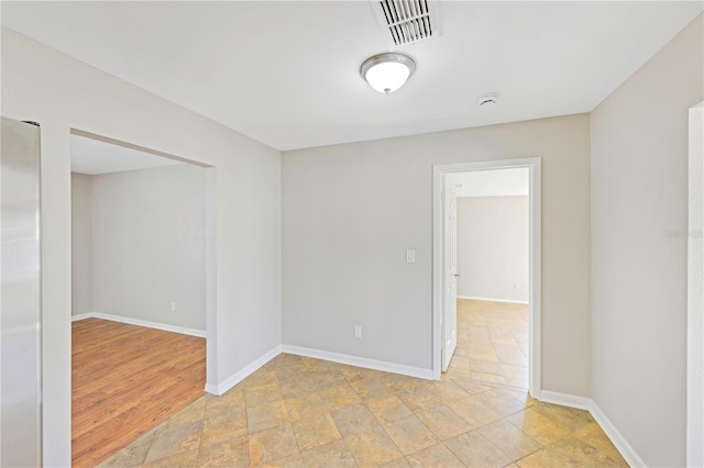 empty room featuring baseboards, stone finish floor, and visible vents