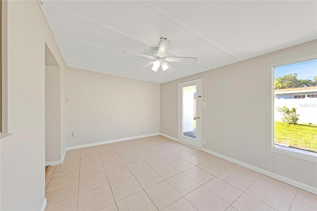 spare room featuring plenty of natural light, baseboards, ceiling fan, and light tile patterned floors