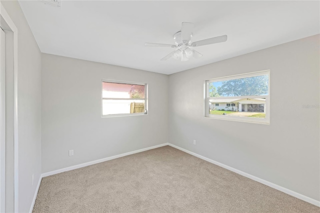 unfurnished room featuring baseboards, ceiling fan, a wealth of natural light, and carpet