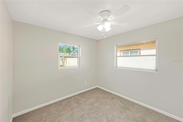 carpeted empty room featuring baseboards and ceiling fan