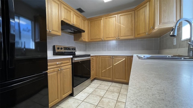 kitchen featuring black refrigerator, sink, stainless steel range with electric cooktop, backsplash, and light tile patterned floors