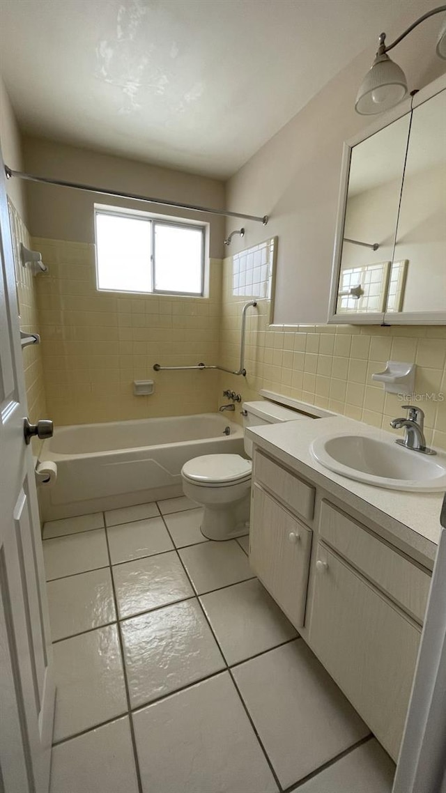 full bathroom with tiled shower / bath, tile walls, vanity, and toilet