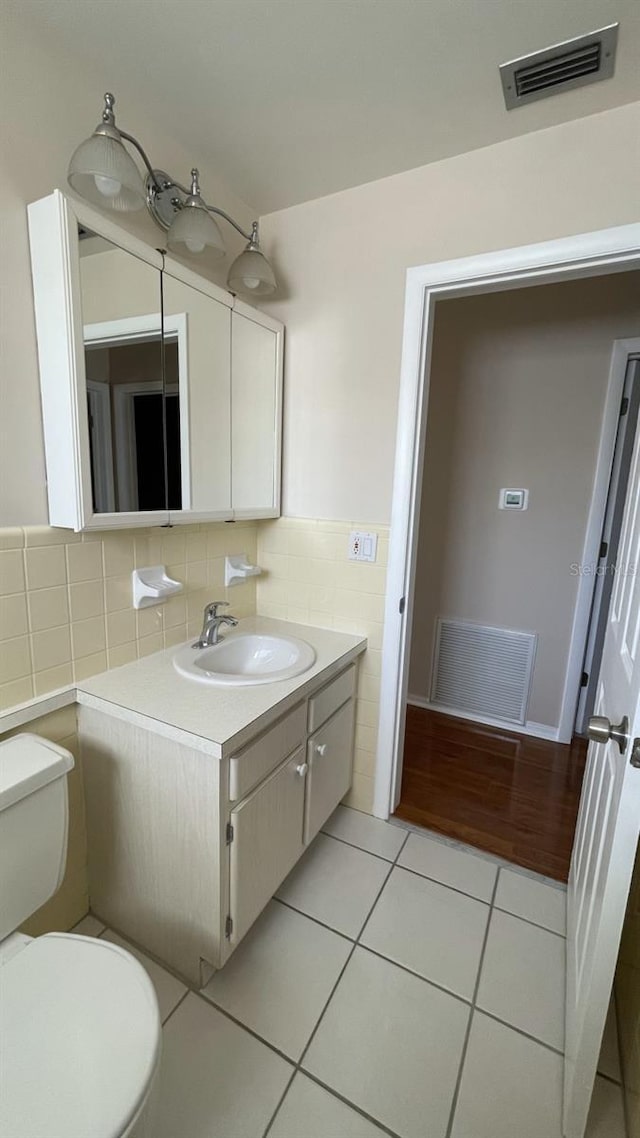 bathroom with vanity, tile walls, tile patterned floors, and toilet