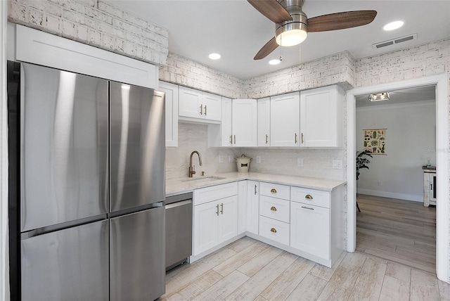 kitchen with visible vents, white cabinets, stainless steel appliances, light wood-type flooring, and a sink