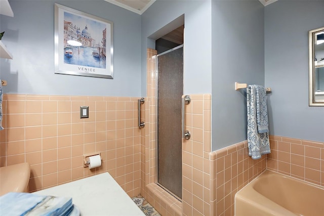 bathroom with a bath, a shower stall, and tile walls