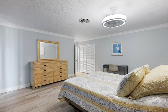 bedroom with crown molding, light wood finished floors, a closet, visible vents, and baseboards