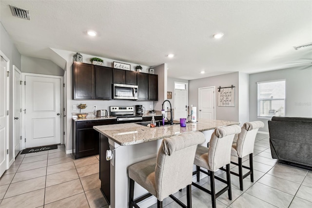 16126 Sunday Stroll Way, Odessa, FL 33556 - kitchen with appliances with stainless steel finishes, a sink, a breakfast bar area, light tile patterned flooring, and an island with sink