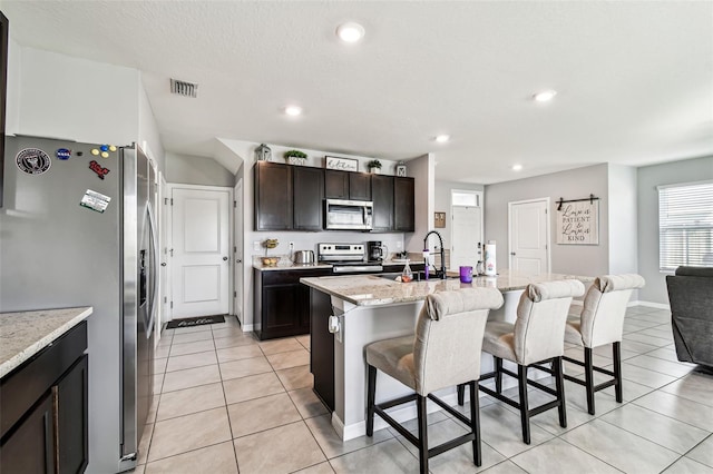 16126 Sunday Stroll Way, Odessa, FL 33556 - kitchen featuring appliances with stainless steel finishes, a sink, a breakfast bar area, light tile patterned floors, and an island with sink