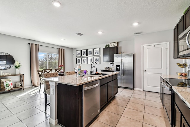 16126 Sunday Stroll Way, Odessa, FL 33556 - kitchen with appliances with stainless steel finishes, a sink, light tile patterned flooring, a kitchen island with sink, and recessed lighting