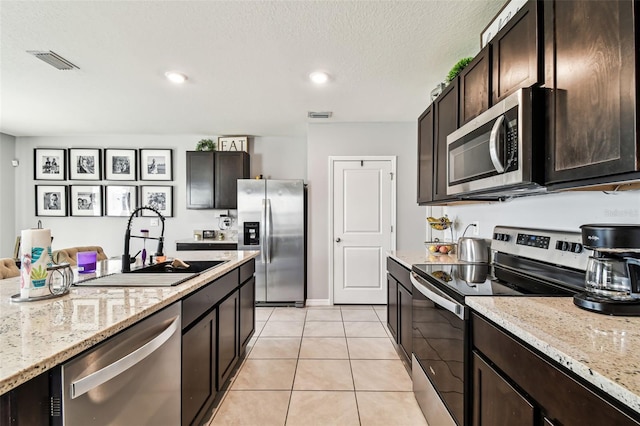 16126 Sunday Stroll Way, Odessa, FL 33556 - kitchen with stainless steel appliances, a sink, dark brown cabinets, light tile patterned floors, and light stone countertops