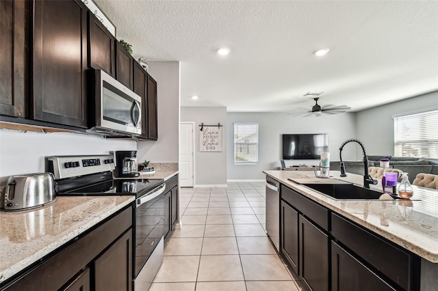 16126 Sunday Stroll Way, Odessa, FL 33556 - kitchen featuring stainless steel appliances, a sink, open floor plan, dark brown cabinets, and light tile patterned floors