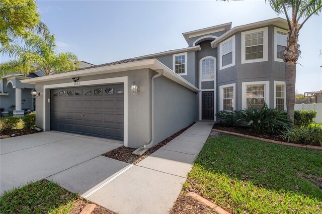 traditional-style home with stucco siding, driveway, and a garage