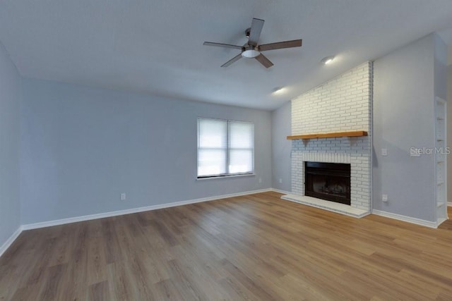 unfurnished living room with ceiling fan, a brick fireplace, vaulted ceiling, and hardwood / wood-style floors