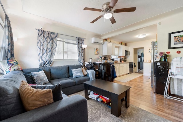 living room with light wood-style floors, a wall unit AC, and a ceiling fan