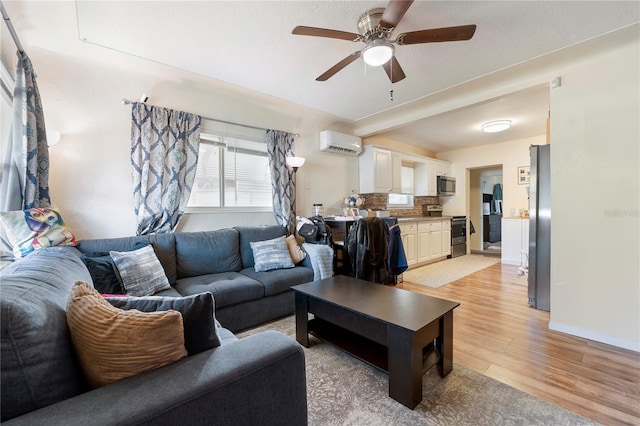 living area featuring a ceiling fan, baseboards, light wood finished floors, and a wall mounted AC