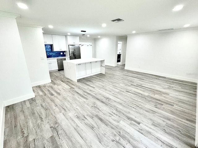 kitchen featuring a kitchen island, visible vents, open floor plan, light countertops, and appliances with stainless steel finishes