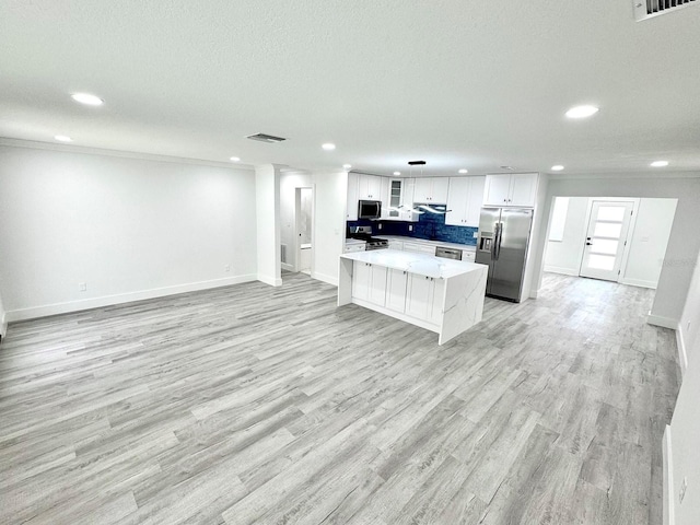 kitchen featuring crown molding, appliances with stainless steel finishes, light wood-style floors, open floor plan, and white cabinets