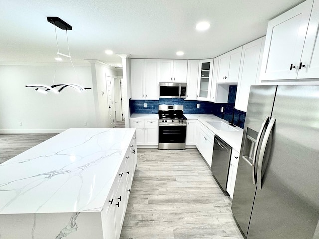 kitchen featuring stainless steel appliances, white cabinets, glass insert cabinets, and hanging light fixtures